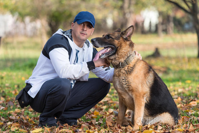 和德国牧羊犬一起坐在户外的成年男子