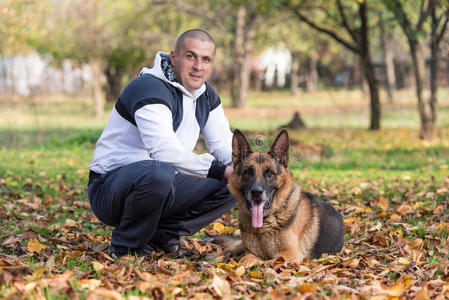 和德国牧羊犬一起坐在户外的成年男子