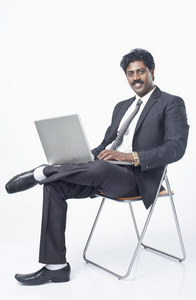 坐在椅子上用笔记本电脑的南印度商人