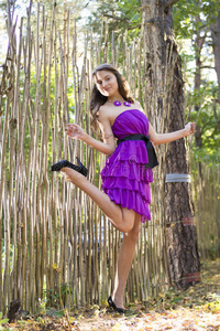 在柳条篱笆附近穿紫罗兰色衣服的漂亮女孩