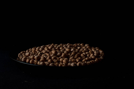在一个木制的罐在黑暗的表面背景生鹰嘴豆的颗粒