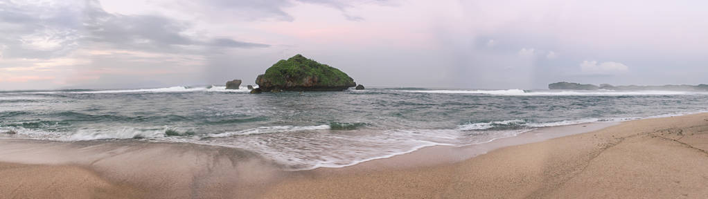 全景的海滩与海浪和珊瑚岛位于海中央。用蓝天装饰