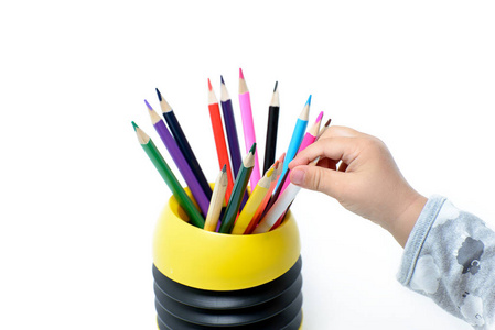 孩子们的手用彩色铅笔从杯子里拿出铅笔