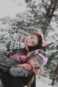 两个年轻的少女时髦女孩朋友在一起。关闭了的两个姐妹拥抱时尚肖像和乐趣冬天的时候，穿着粉红色的帽子，兔子耳朵，毛衣，最好的朋友夫妇