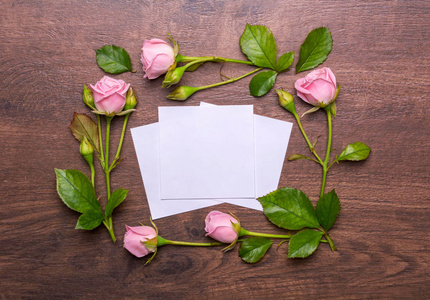 娇嫩的小花的圆形框架。在一个木制的背景上的粉红玫瑰。纸与空地方为文本