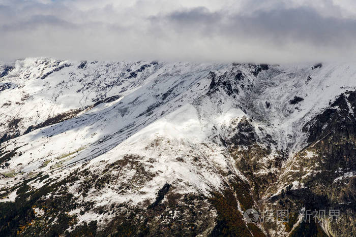 高加索山脉在冬天被雪覆盖，上面有多云的天空。
