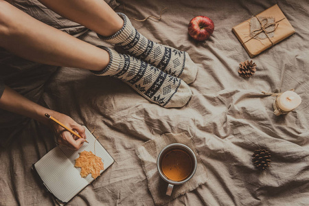 舒适的家里。写在记事本中的热饮料杯的女人。顶视图