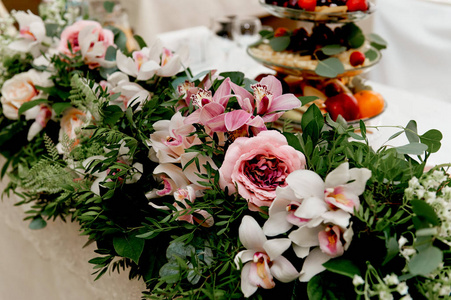 婚礼表装饰新婚夫妇。在鲜花的桌子上的歌曲。粉红色和白色的调色板 玫瑰 兰花