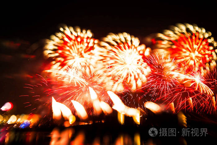 抽象模糊散景风格的烟花在河上方的红色调一张彩色照片