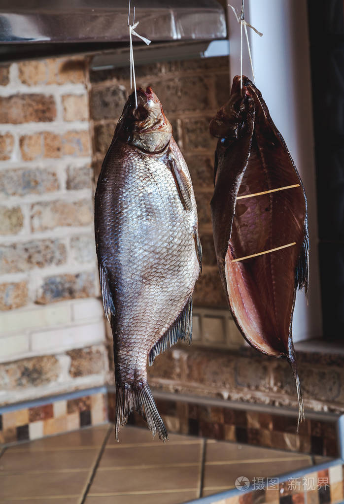 上砖的背景墙上挂着的两个大烟熏的鱼