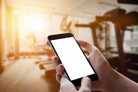 男人手里拿空屏幕的智能手机设备在健身房