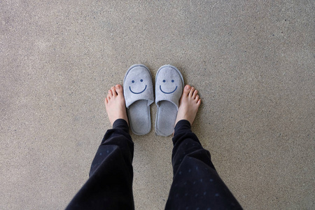 灰色拖鞋, 关闭女人的脚穿微笑灰色拖鞋在水泥背景照片