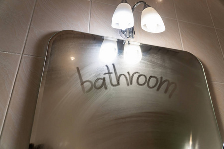 在汗流满面的镜子上, 浴室 这个词被写了出来