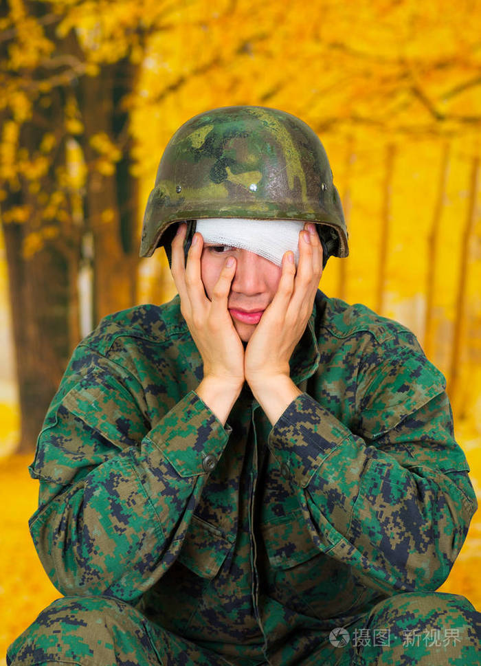 年轻英俊的士兵穿着统一遭受压力,与白色的绷带,在他的头和覆盖他的