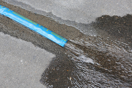 水通过排水沟的沥青盖流出照片