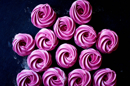 很多紫色是深色表面上的棉花糖。对比鲜明的图片。烹饪艺术作品