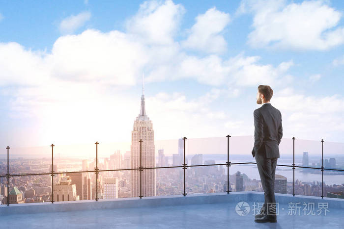 望着远处的屋顶上的年轻的商人的背影.城市与副本空间的背景.