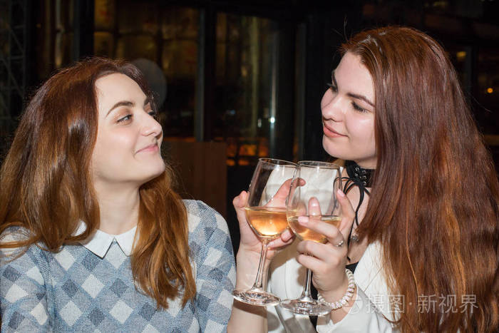 两位女性朋友在餐馆喝白葡萄酒的亲密关系
