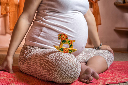 紧靠 40 周孕妇的肚子。女人怀孕与可爱小木马玩具锐化在她的肚子