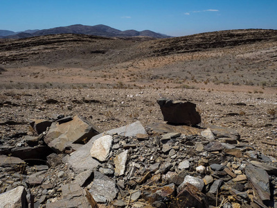 天然岩石山干尘土飞扬的景观地面纳米比亚布沙漠与分裂页岩片断, 其他石头和沙漠植物