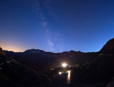 七彩发光银河系拱门和满天星斗的天空，从阿尔卑斯山的高处。水电湖大坝的灯