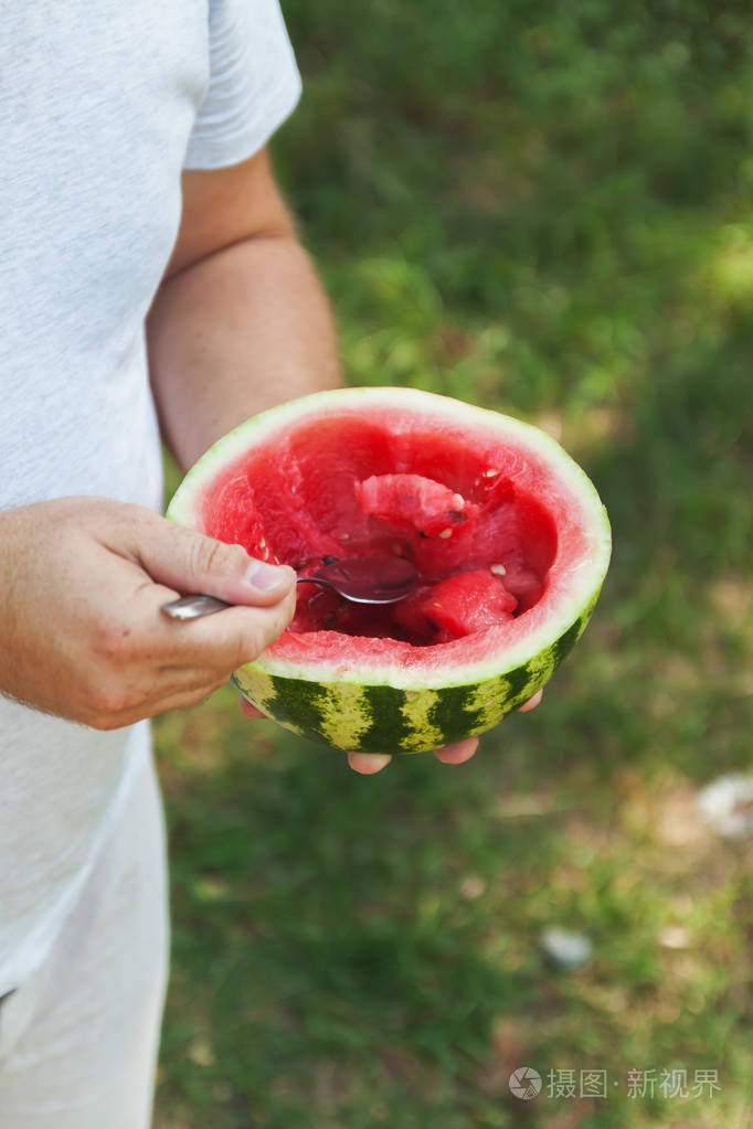 一名年轻男子正在用勺子吃西瓜概念