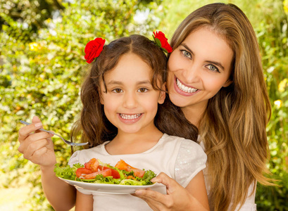 漂亮的年轻妈妈和女儿准备吃健康的沙拉