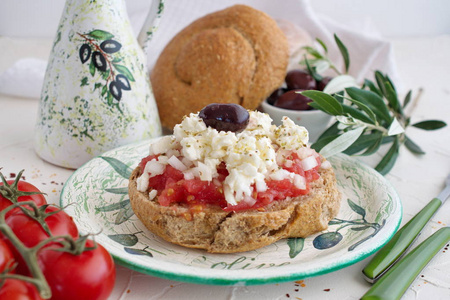 Dakos 在传统盘子里陶瓷橄榄油罐子 干黑麦面包 橄榄和橄榄枝的传统希腊开胃菜。健康饮食的概念。地中海的生活方式