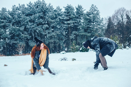 男孩和女孩在冬季树林里休息。丈夫和妻子在雪地里。年轻夫妻在冬季公园散步