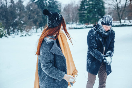 男孩和女孩在冬季树林里休息。丈夫和妻子在雪地里。年轻夫妻在冬季公园散步