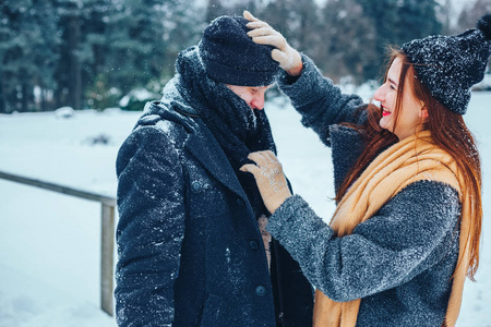 男孩和女孩在冬季树林里休息。丈夫和妻子在雪地里。年轻夫妻在冬季公园散步