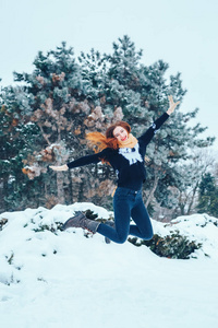 红发的年轻女子在冬季森林中的红围巾