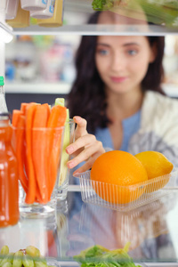 女性站附近打开冰箱充分的健康食品，蔬菜和水果的画像。女性肖像