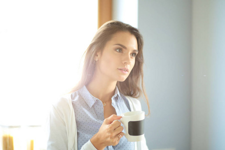 幸福的女人在家里的厨房里喝着茶。在家里的女人