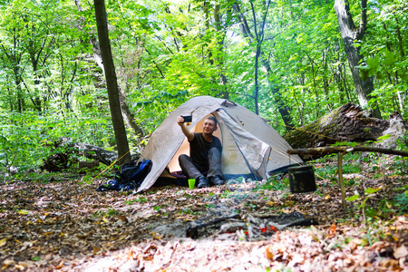 在森林里的篝火和一个旅游帐篷, 游客在帐篷附近休息