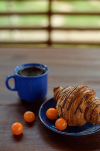 早餐 蓝杯茶，巧克力羊角面包和酸浆木制的桌子上