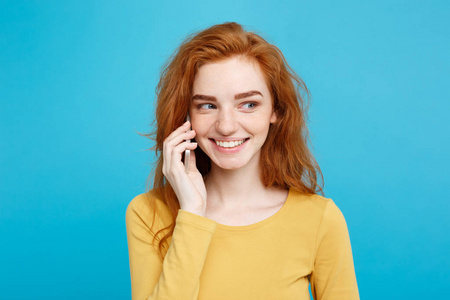 生活方式和技术的概念   通过手机和朋友谈话既高兴又兴奋的开朗快乐姜红头发女孩的画像。柔和的蓝色背景上的孤立。复制空间