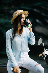 快乐年轻时髦女人在早上喝酒靠近她的脚踏车外卖咖啡