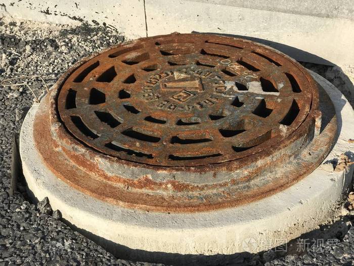 生锈的铁井眼设置在沥青路面