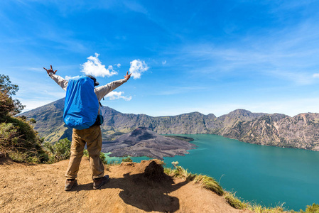 传播的手，背包徒步旅行者人享受和满意活火山巴鲁杰瑞，湖塞格拉衲和首脑会议的瑞嘉尼山景后完成攀爬在印度尼西亚龙目岛的瑞嘉尼山