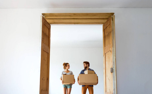年轻夫妇搬进新房子，抱着箱子