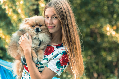 一个女孩走着一个公园，一只狗。博美犬施皮茨