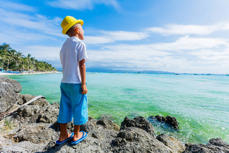 在热带海洋沙滩上玩耍的男孩。孩子在家庭海度假期间