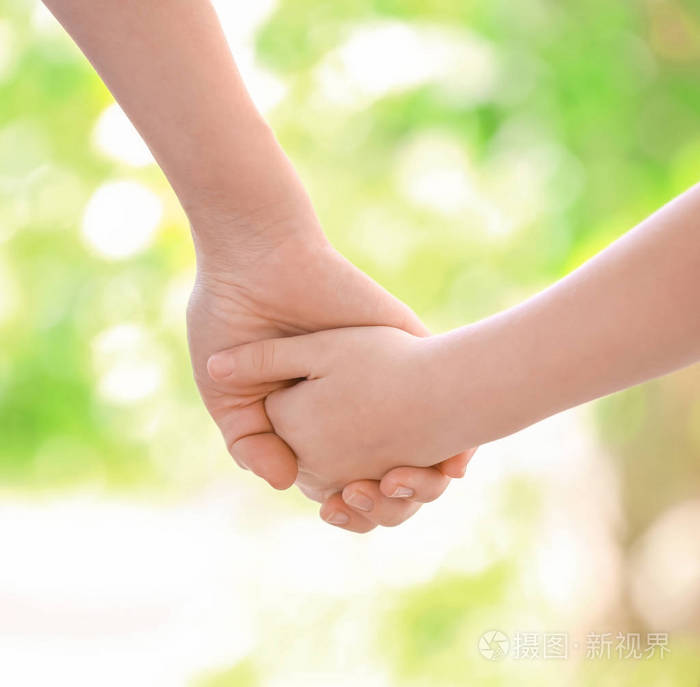 母女牵手在模糊的背景下