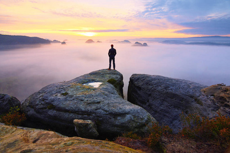 满足的徒步旅行者欣赏的景色.高个子男人在悬崖上照片