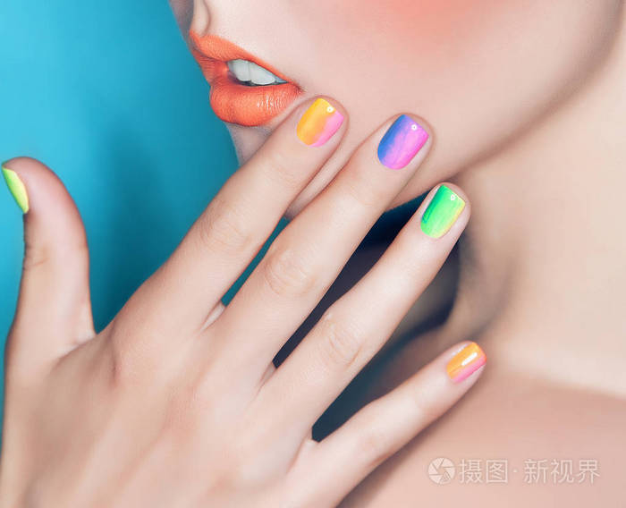 美丽的女性嘴唇和手与彩虹指甲指甲与化妆特写