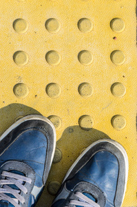 黄色触觉铺装板上的蓝色运动鞋图片