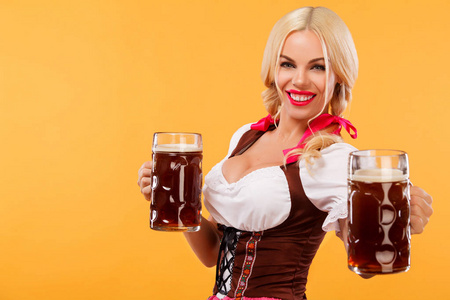 年轻慕尼黑啤酒节服务员，穿连衣裙的女孩传统巴伐利亚，服务大啤酒杯上橙色背景