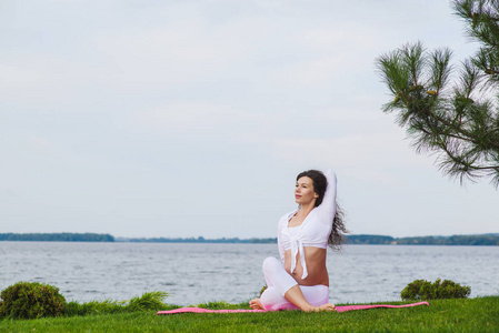 怀孕的女人练瑜伽在河旁边