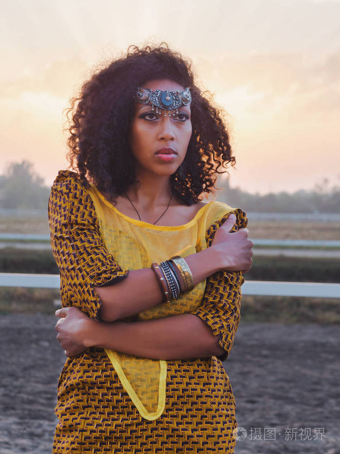 年轻的美国黑人吉普赛女人多彩的黄色传统服饰和银色皇冠微笑和舞近